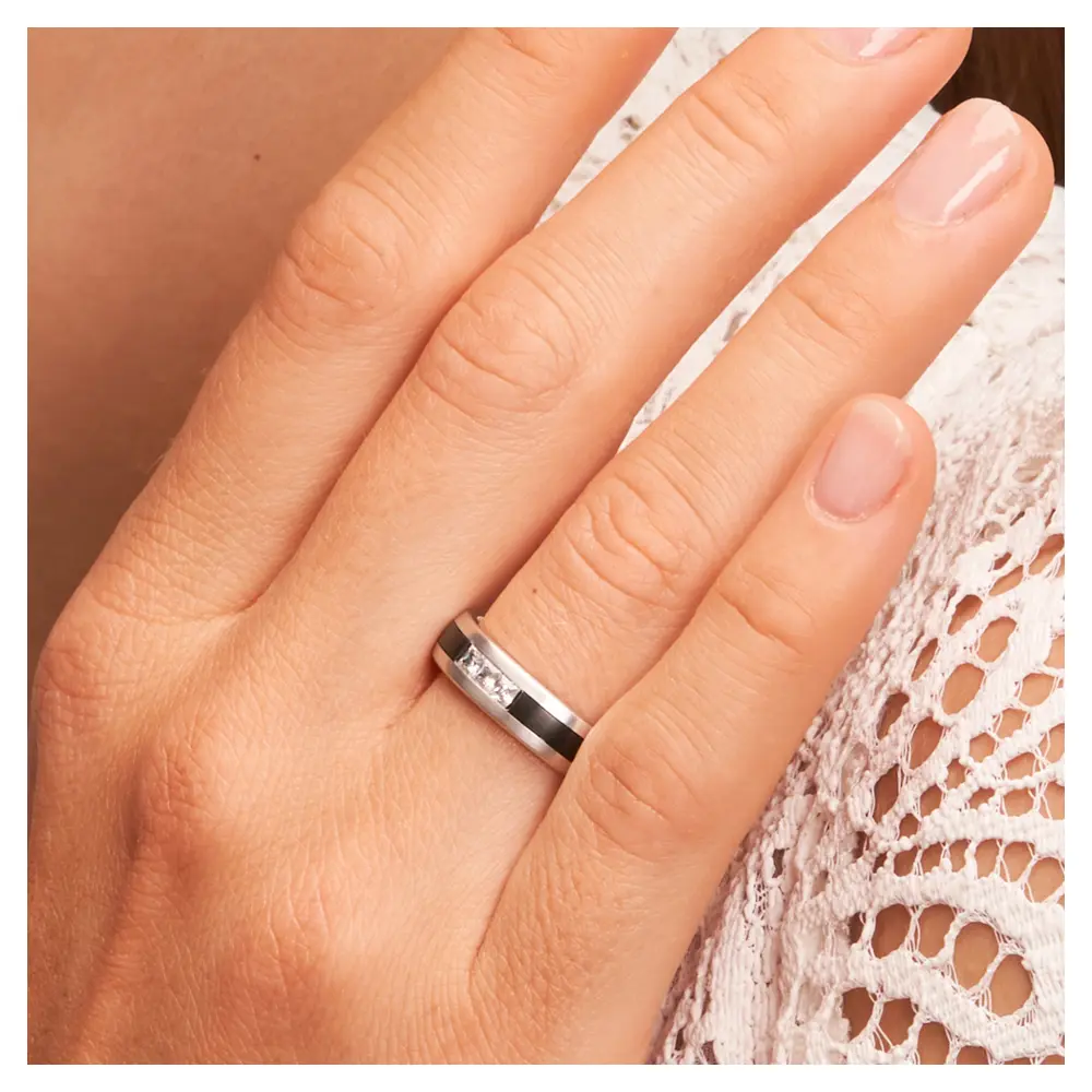 Trauring aus Weißgold und Zirkonium bicolor mit drei Diamanten auf Hand am Gesicht im Zoom