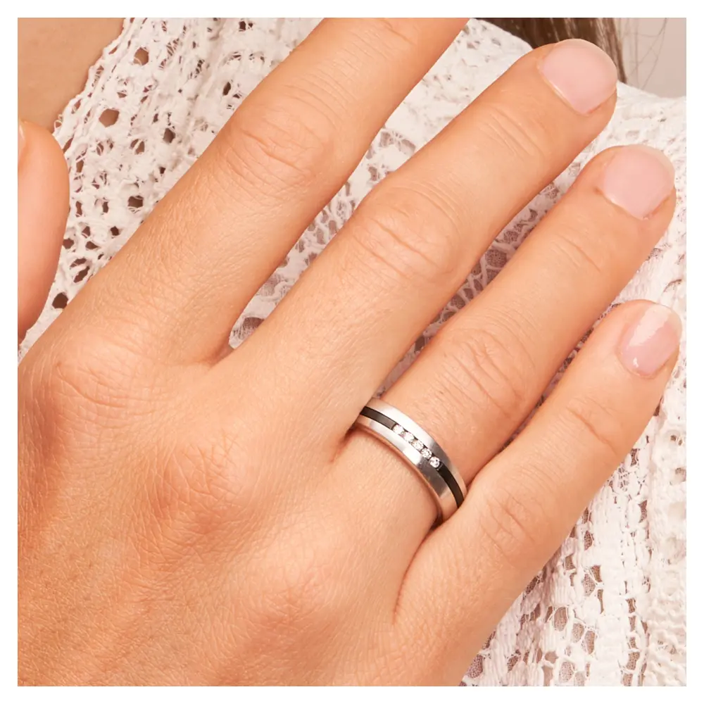 Ehering aus Weißgold mit Zirkoniumstreifen und fünf süßen Diamanten auf Hand am Gesicht
