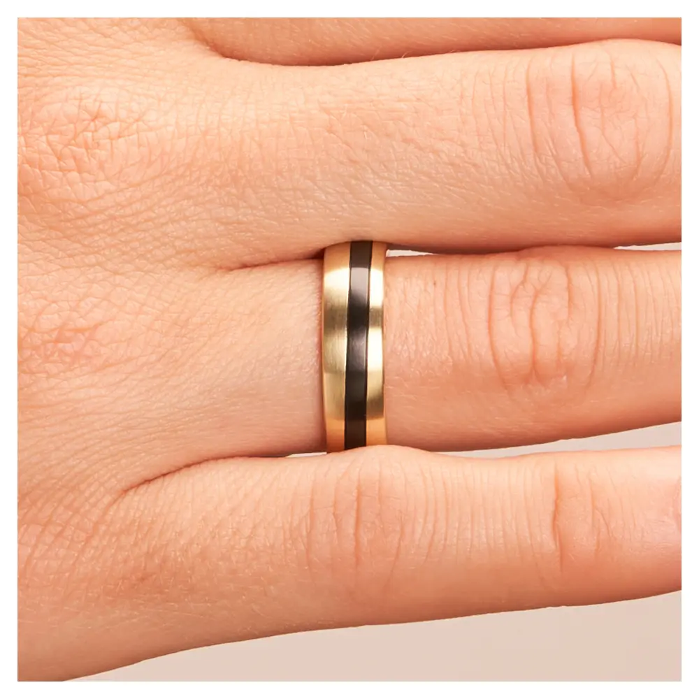 Trauringe aus Gelbgold & Zirkonium bicolor auf Hand im Zoom
