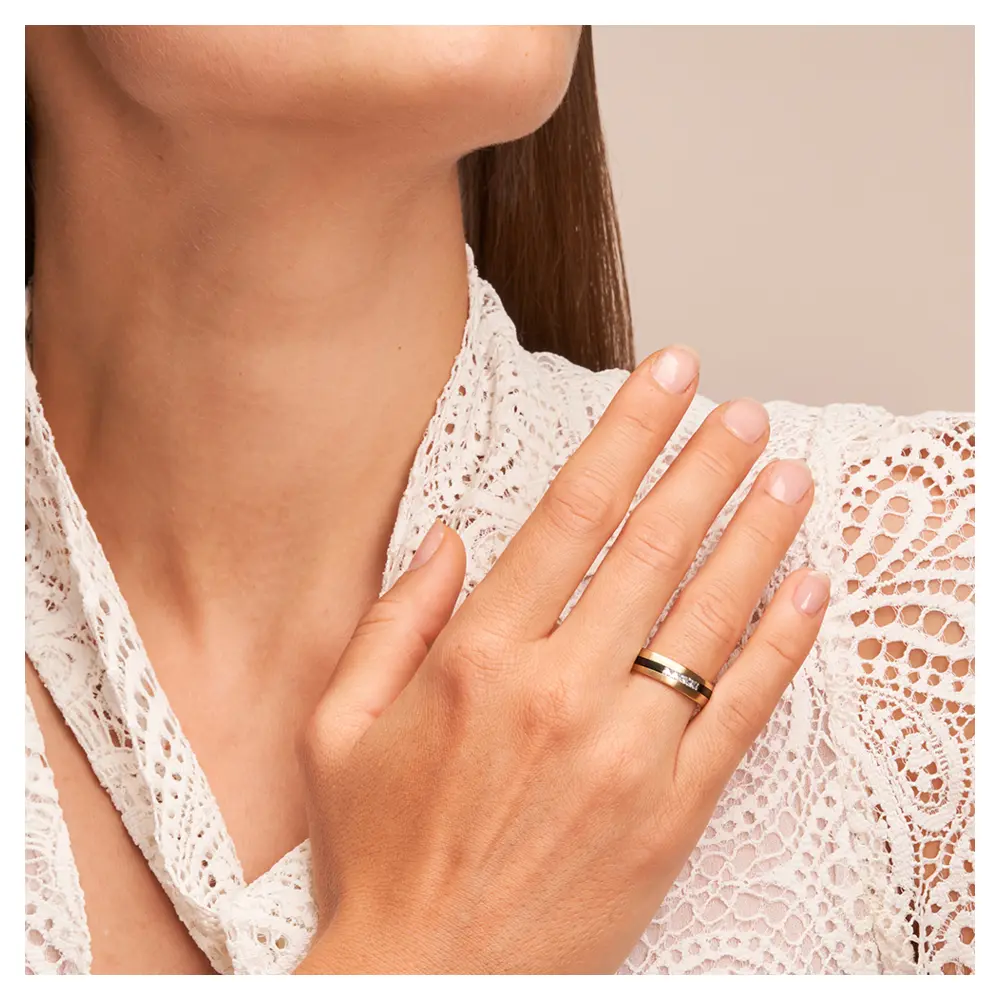 Trauringe aus Gelbgold & Zirkonium bicolor mit fünf Diamanten auf Hand am Gesicht