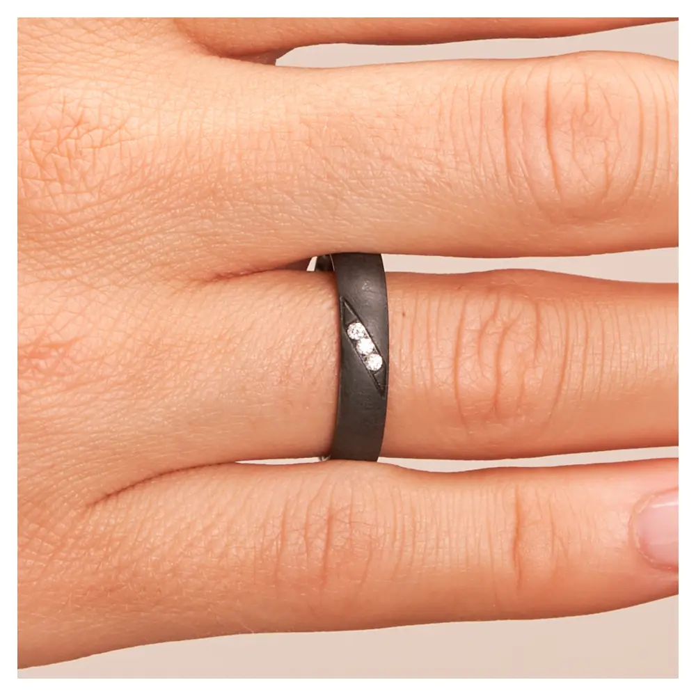 Ehering aus Zirkonium mit 3 Diamanten und besonderer Oberfläche auf Hand im Zoom