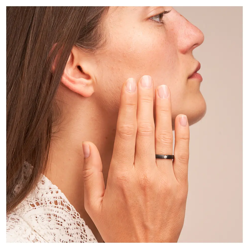 Ehering aus Zirkonium in zwei Breiten mit Diamanten auf Hand am Gesicht