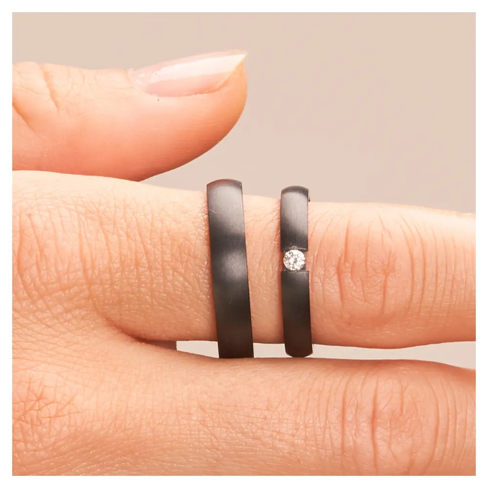 Eheringe aus Zirkonium in zwei Breiten mit Diamanten auf der Hand im Zoom