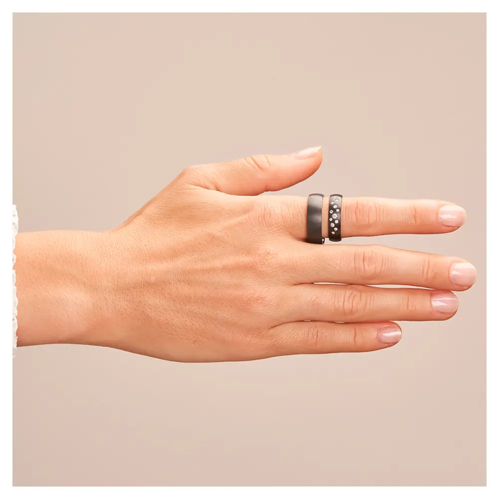 Eheringe aus schwarzem längsmattem Zirkonium mit vielen weißen Diamanten auf Hand