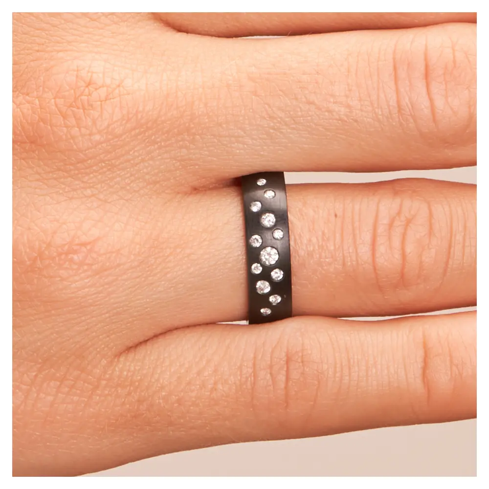 Ehering aus schwarzem längsmattem Zirkonium mit vielen weißen Diamanten auf Hand im Zoom