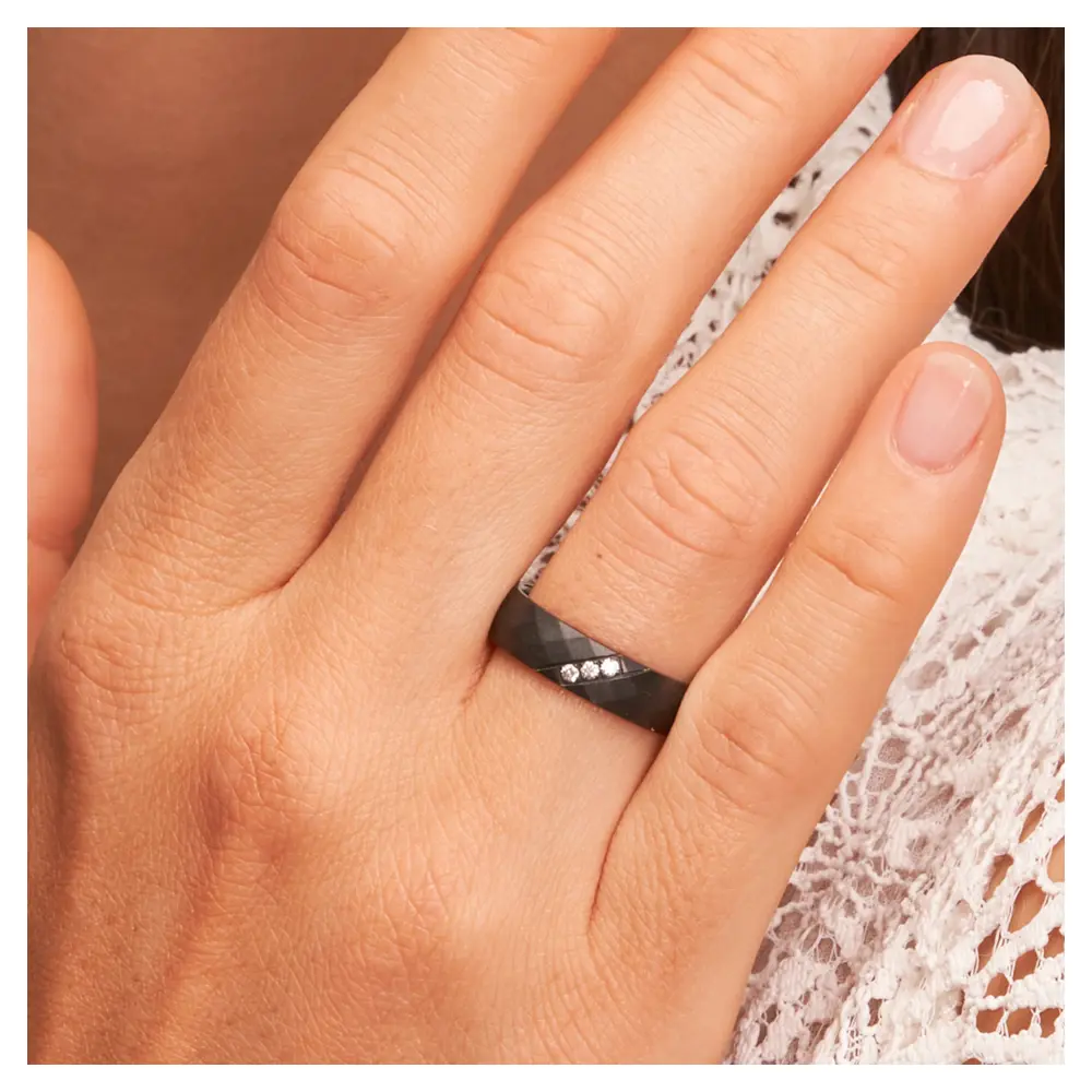Ehering aus Zirkonium mit strukturierter Oberfläche und 3 Diamanten auf Hand am Gesicht im Zoom