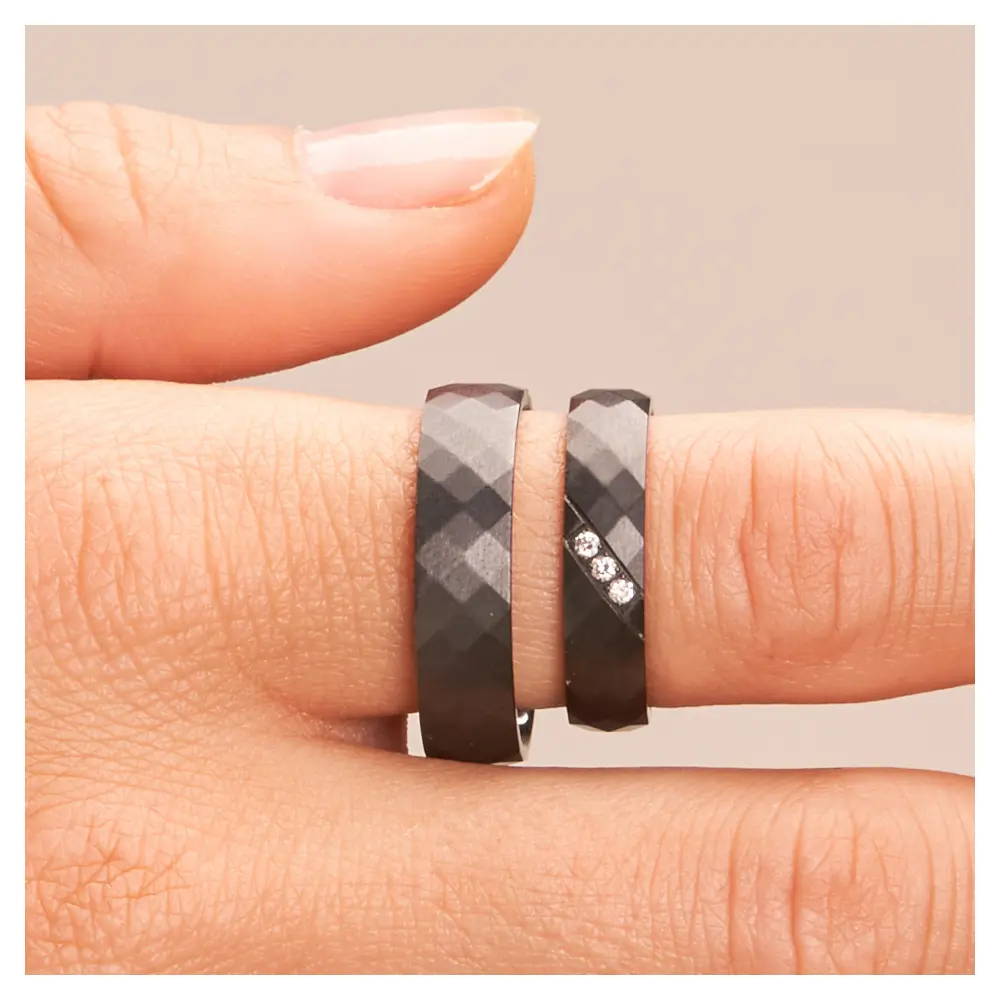 Eheringe aus Zirkonium mit strukturierter Oberfläche und 3 Diamanten auf Hand im Zoom
