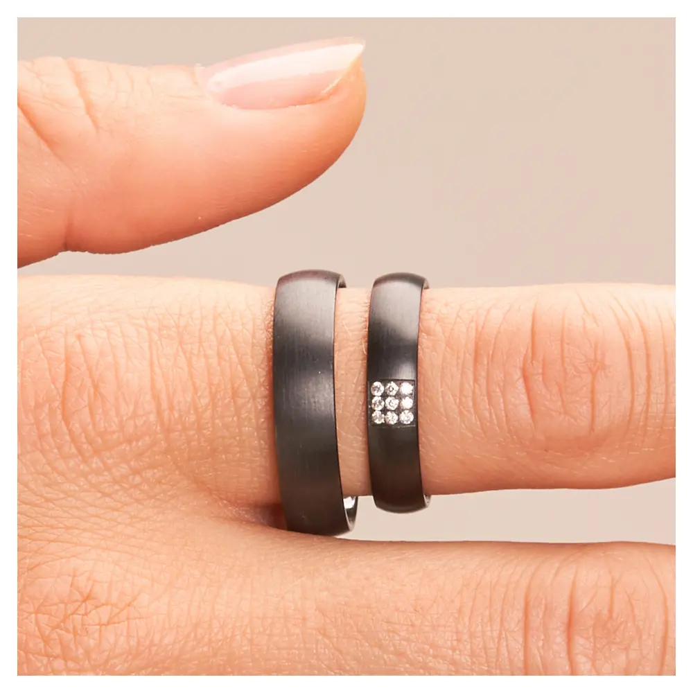 Eheringe aus Zirkonium mit Diamanten als strahlendes Quadrat auf Hand im Zoom