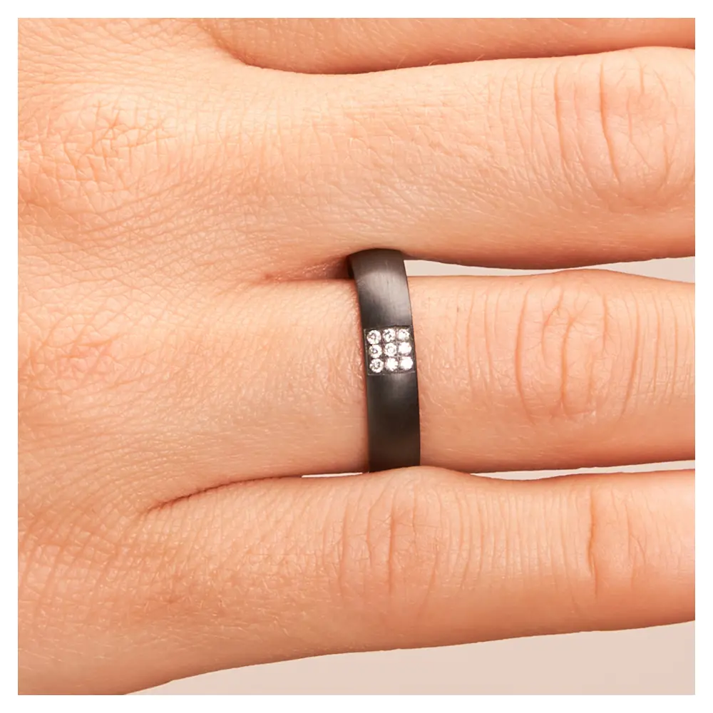 Ehering aus Zirkonium mit Diamanten als strahlendes Quadrat auf Hand im Zoom