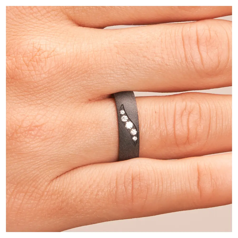 Schimmernder schwarzer Ehering aus Zirkonium mit fünf Diamanten auf Hand im Zoom