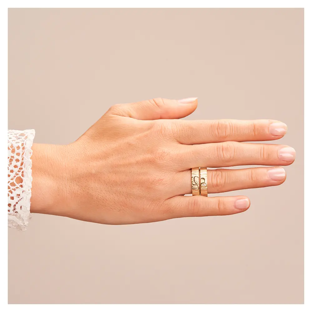 Eheringe aus Gelbgold mit geriffelter Oberfläche und zwei Diamanten auf Hand