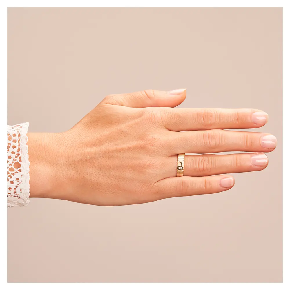Ehering aus Gelbgold mit geriffelter Oberfläche und zwei Diamanten auf Hand