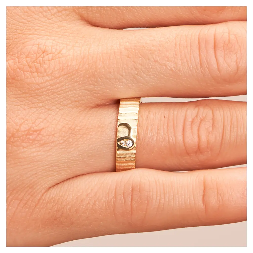 Ehering aus Gelbgold mit geriffelter Oberfläche und zwei Diamanten auf Hand im Zoom