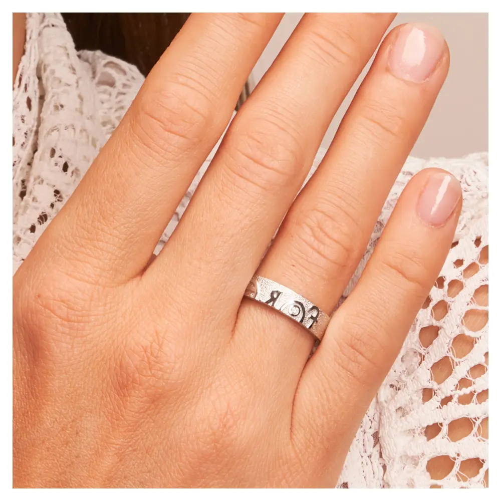 Ehering aus Weißgold mit Forever-Schriftzug und weißem Brillant auf Hand am Gesicht im Zoom