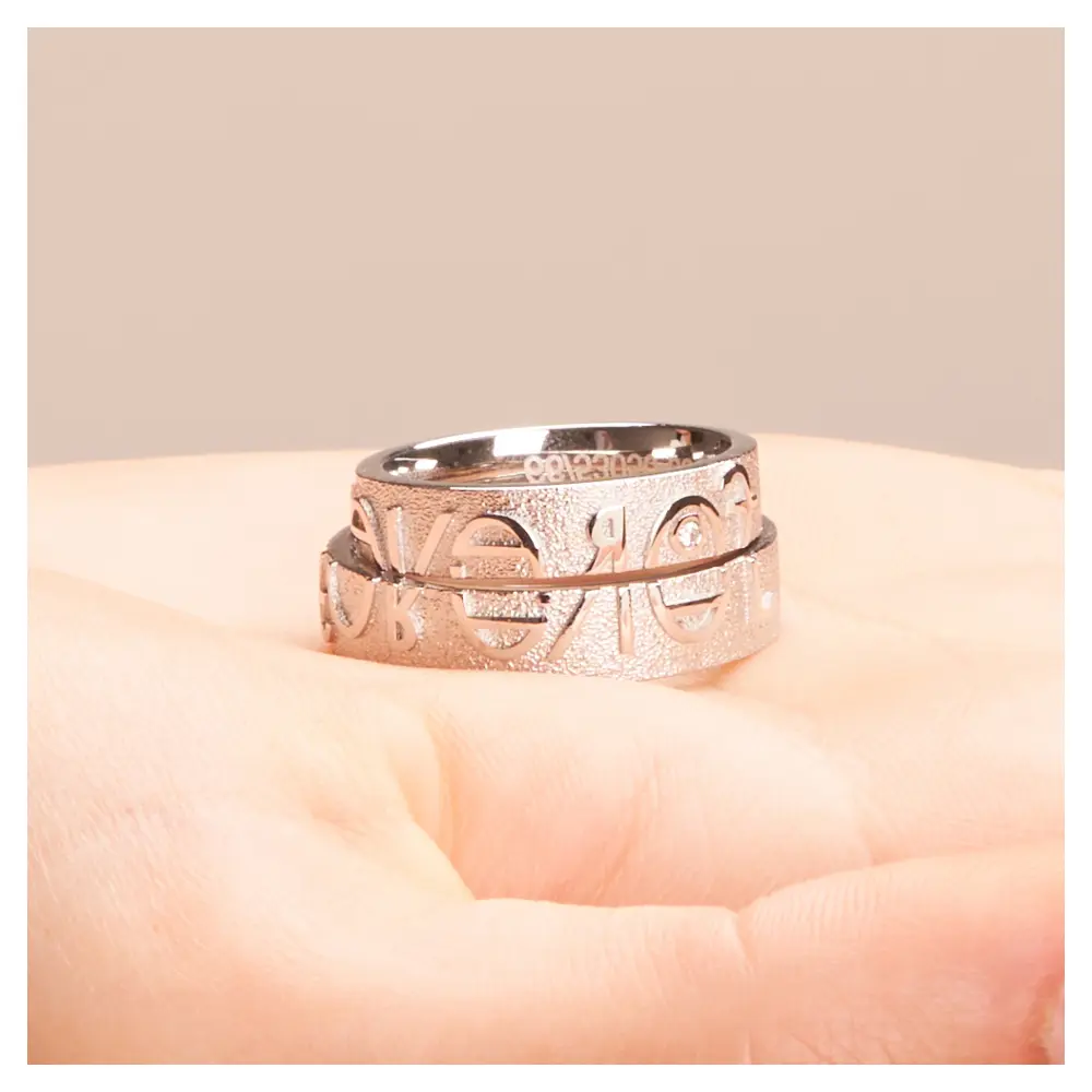 Eheringe aus Weißgold mit Forever-Schriftzug und weißem Brillant auf Hand horizontal im Zoom