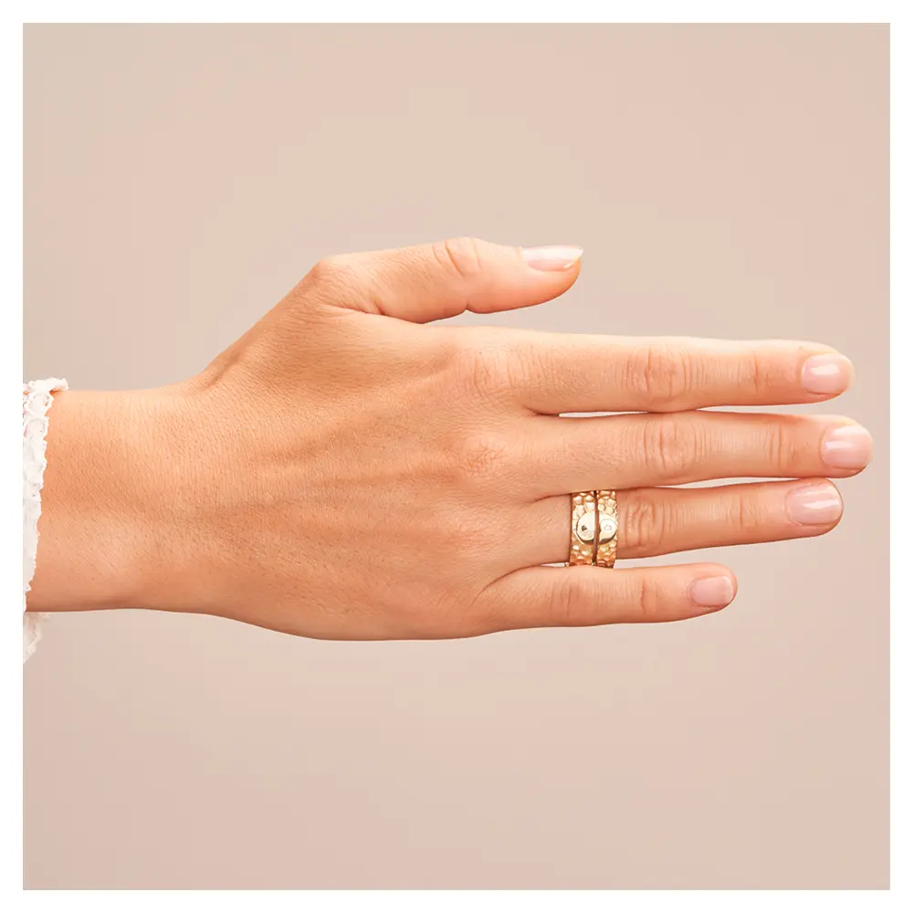 Eheringe aus Gelbgold in Hammerschlag-Optik und Yin & Yang-Symbol auf Hand