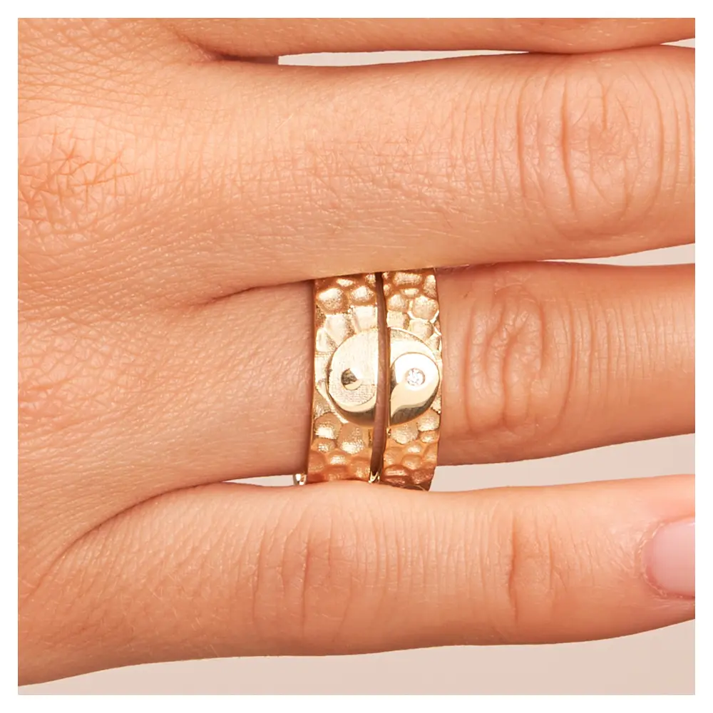 Eheringe aus Gelbgold in Hammerschlag-Optik und Yin & Yang-Symbol auf Hand im Zoom