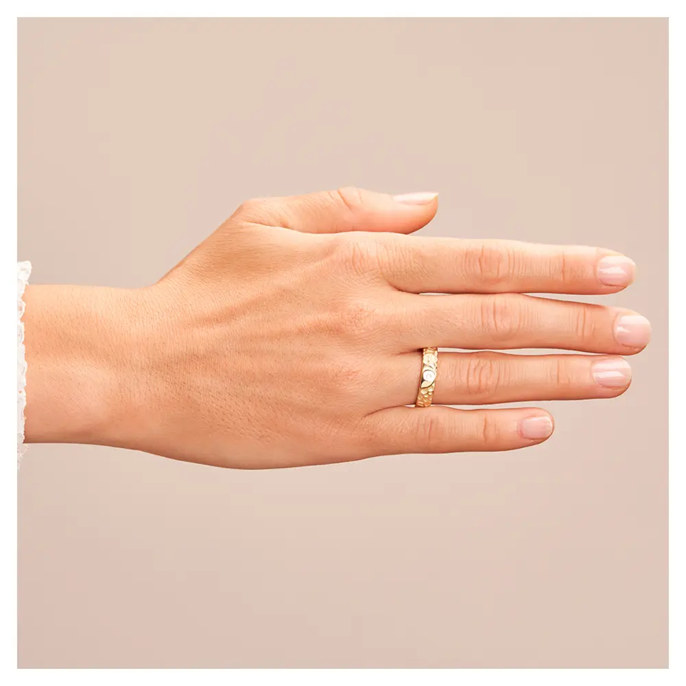 Ehering aus Gelbgold in Hammerschlag-Optik und Yin & Yang-Symbol auf Hand