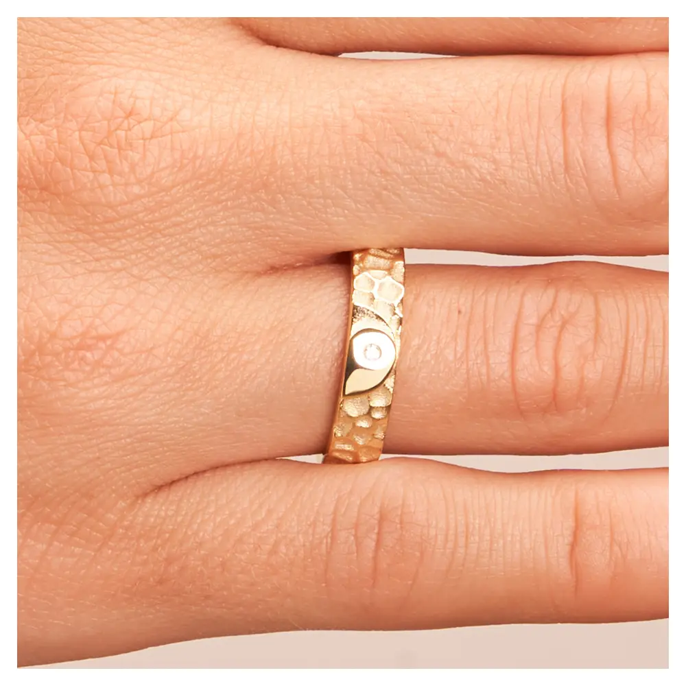 Ehering aus Gelbgold in Hammerschlag-Optik und Yin & Yang-Symbol auf Hand im Zoom
