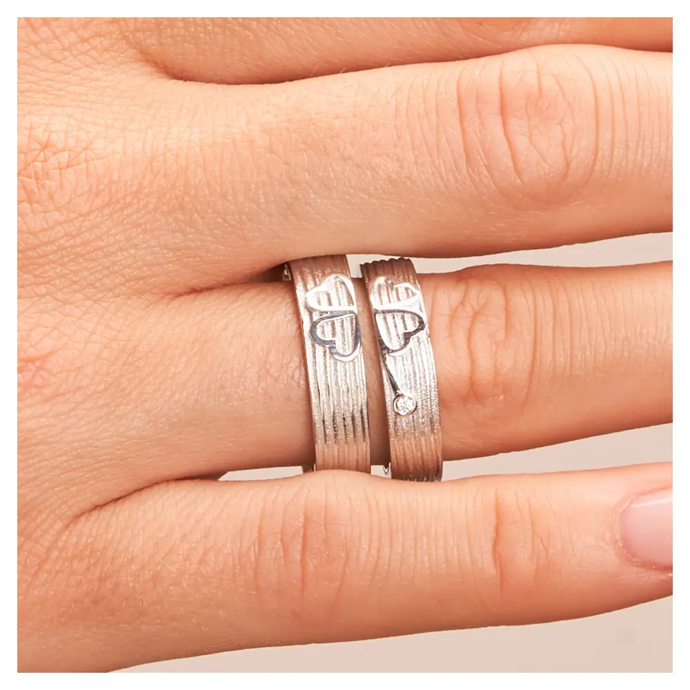 Eheringe aus Weißgold mit einem Kleeblatt als Symbol und Diamant auf Hand im Zoom