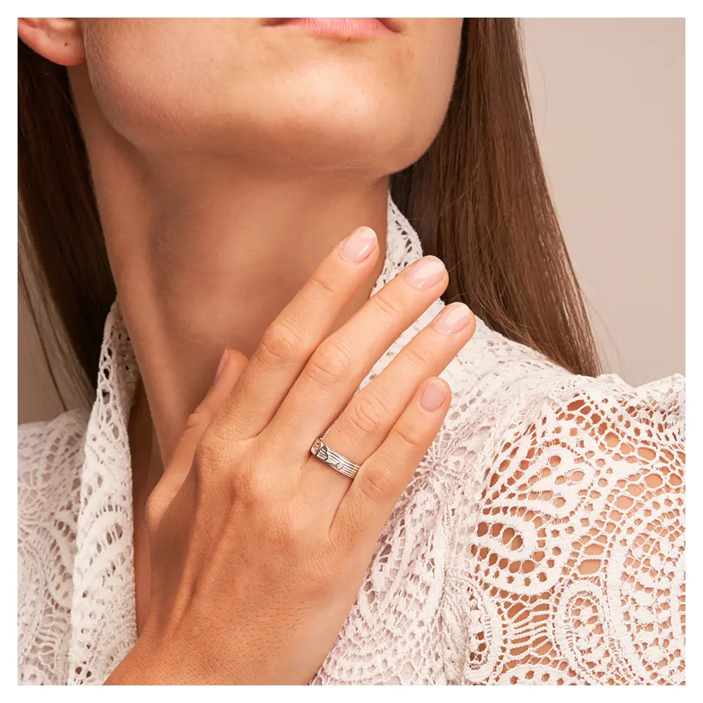 Ehering aus Weißgold mit einem Kleeblatt als Symbol und Diamant auf Hand am Gesicht