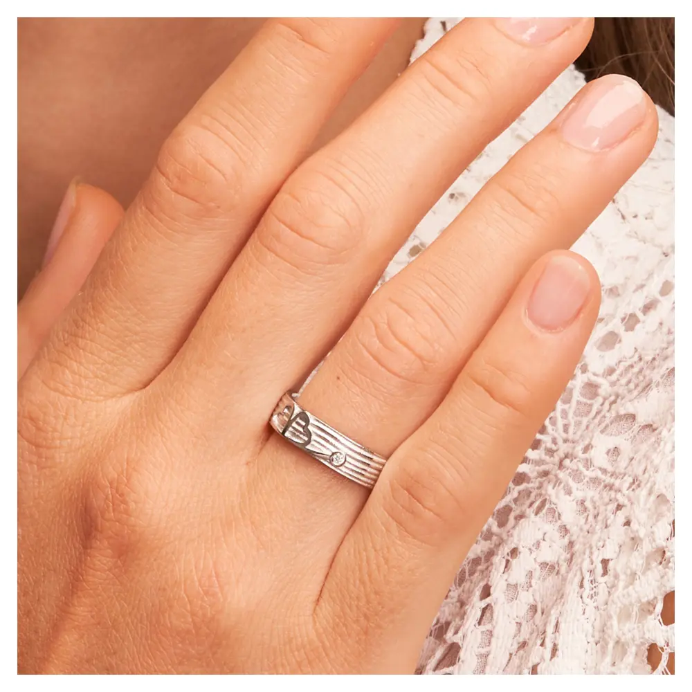 Ehering aus Weißgold mit einem Kleeblatt als Symbol und Diamant auf Hand am Gesicht im Zoom