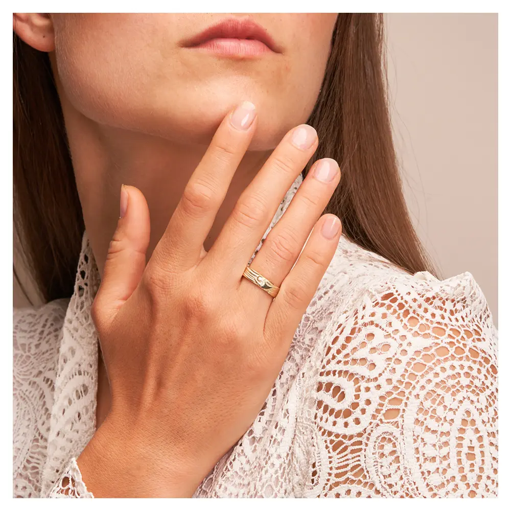 Ehering aus Gelbgold mit interessantem Paarfigur-Symbol auf Hand am Gesicht
