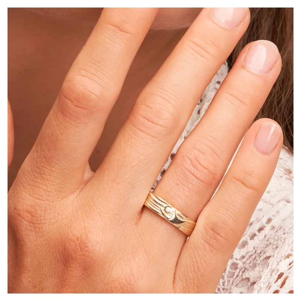 Ehering aus Gelbgold mit interessantem Paarfigur-Symbol auf Hand am Gesicht im Zoom
