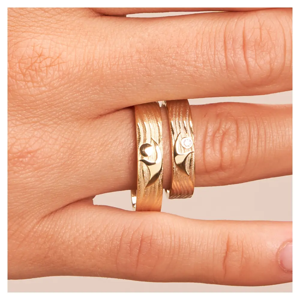 Eheringe aus Gelbgold mit interessantem Paarfigur-Symbol auf Hand im Zoom