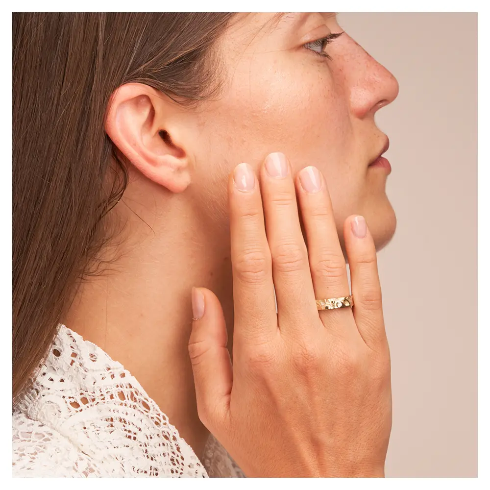 Ehering aus Gelbgold mit Symbol für Glaube Liebe Hoffnung und Brillant auf Hand am Gesicht