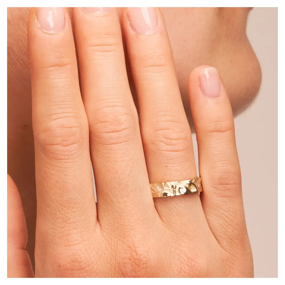 Ehering aus Gelbgold mit Symbol für Glaube Liebe Hoffnung und Brillant auf Hand am Gesicht im Zoom