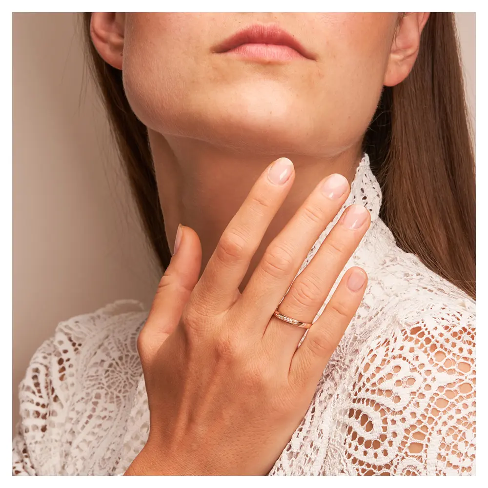 Ehering aus 585 Rotgold & Platin mit 5 Diamanten in diagonaler Rille auf Hand am Gesicht