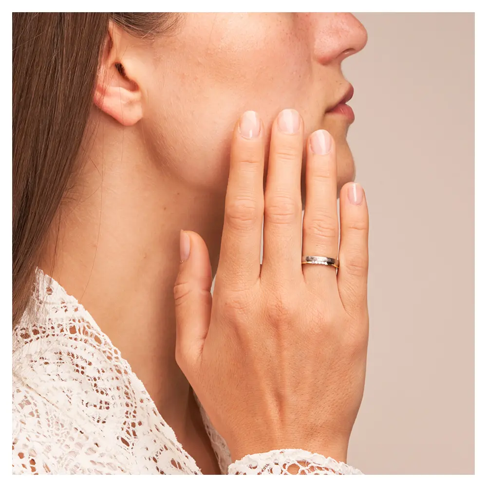 Bicolor Ehering aus 585 Gelbgold & Platin sandmattiert mit 5 Diamanten auf Hand am Gesicht