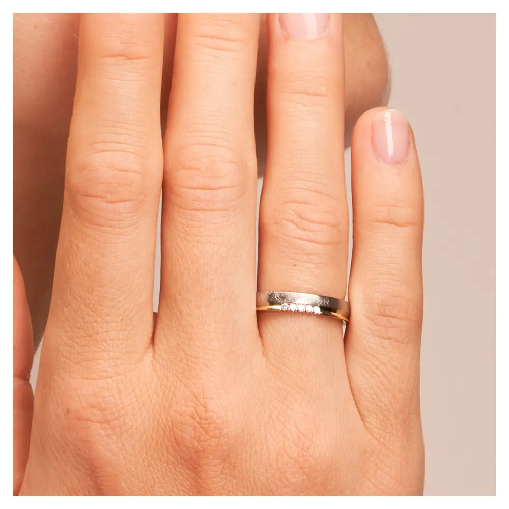Bicolor Ehering aus 585 Gelbgold & Platin sandmattiert mit 5 Diamanten auf Hand am Gesicht im Zoom