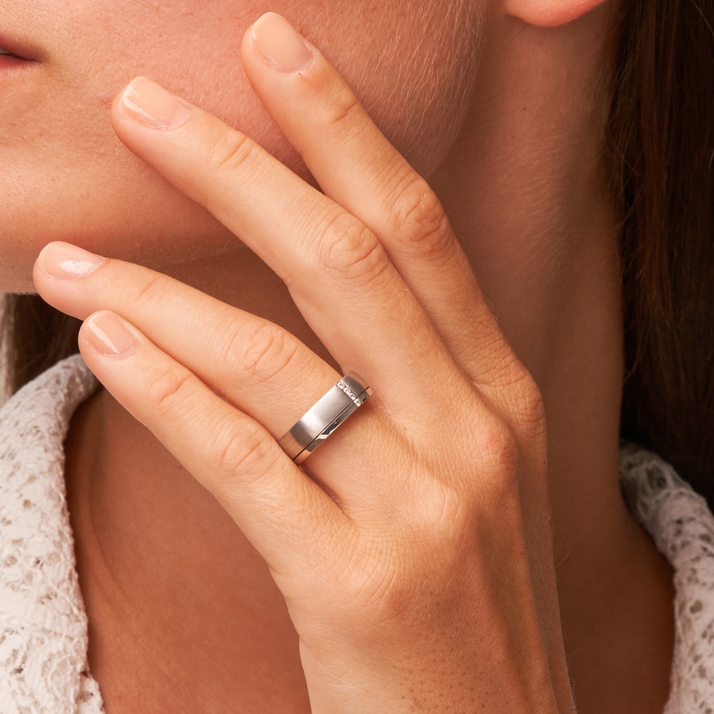 Eckige Eheringe aus Silber mit Mattierung und Diamanten auf Hand in Nahaufnahme