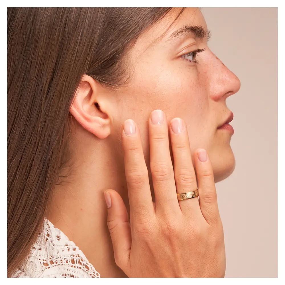 Ehering aus Gelbgold mit keltischem Muster auf Hand am Gesicht