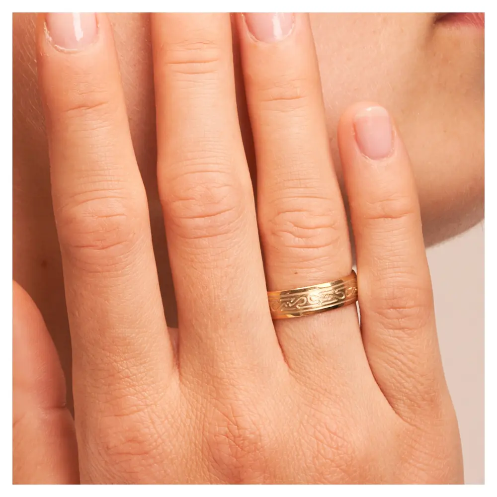 Ehering aus Gelbgold mit keltischem Muster auf Hand am Gesicht im Zoom