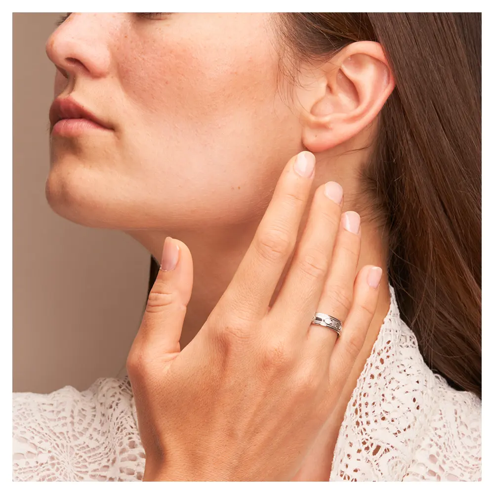 Außergewöhnliche Eheringe aus Weissgold mit interessantem Muster auf Hand am Gesicht