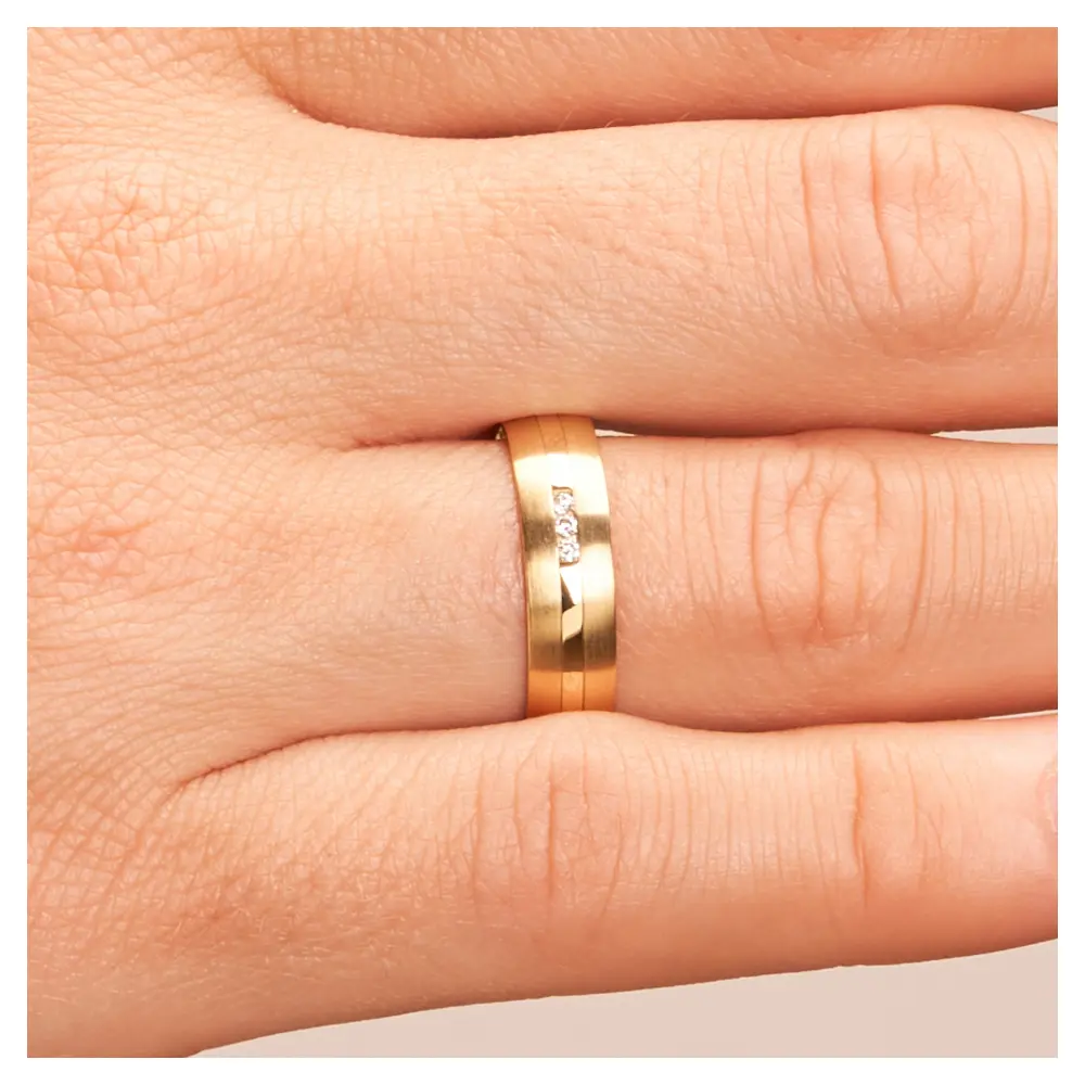 Eheringe aus Gelbgold mit Diamanten und matter Oberfläche auf Hand im Zoom
