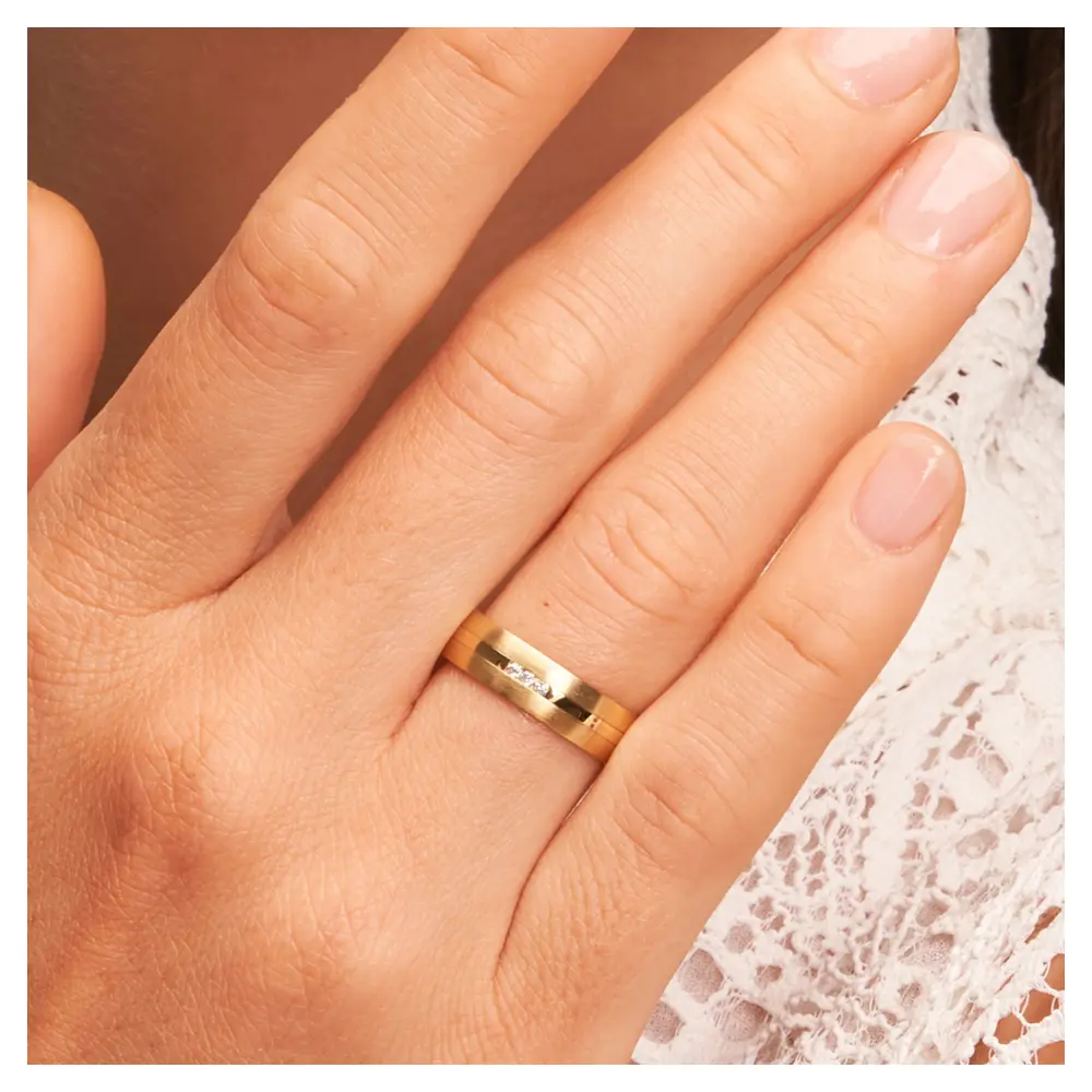 Eheringe aus Gelbgold mit Diamanten und matter Oberfläche auf Hand am Gesicht im Zoom