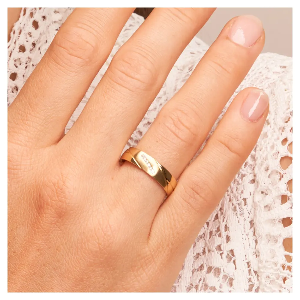 Polierte Eheringe aus Gelbgold mit Rillenmuster und Diamanten auf Hand am Gesicht im Zoom