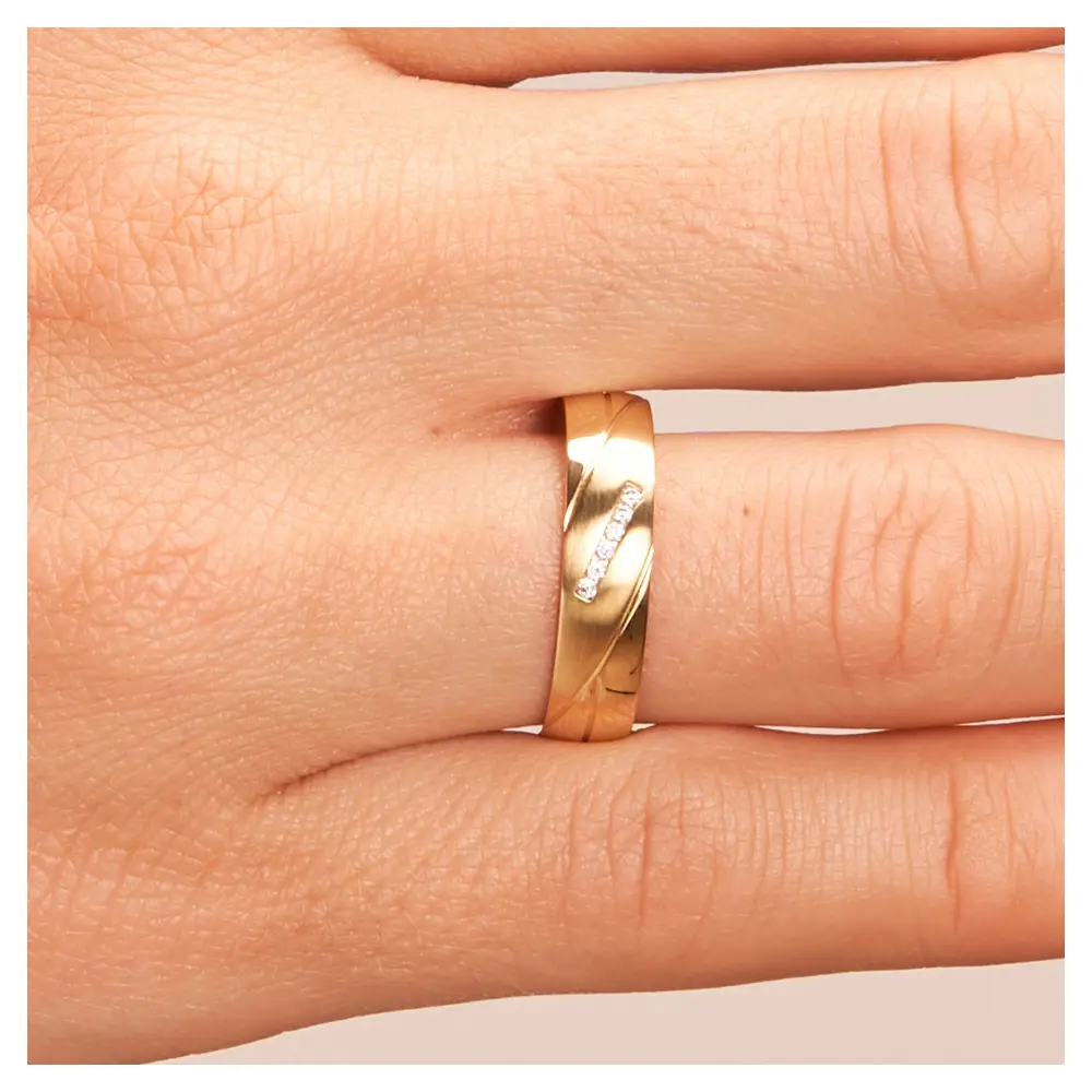 Polierte Eheringe aus Gelbgold mit Rillenmuster und Diamanten auf Hand im Zoom