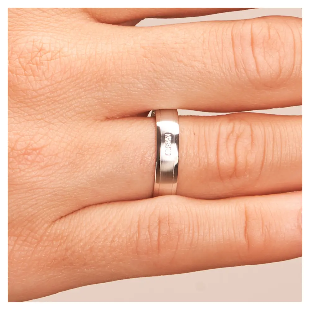 Matte Eheringe aus Weissgold mit polierten Rändern und 3 Diamanten im Kanal auf Hand im Zoom