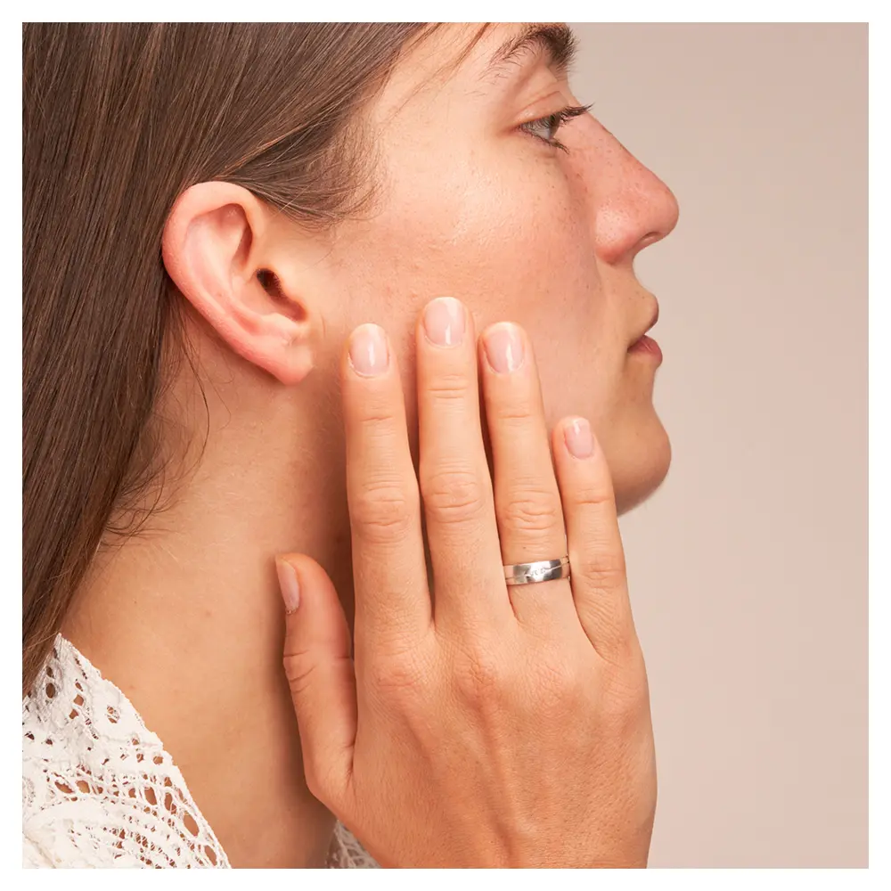 Längsmattierte Eheringe aus Weissgold mit ovaler Rille und Diamanten auf Hand am Gesicht