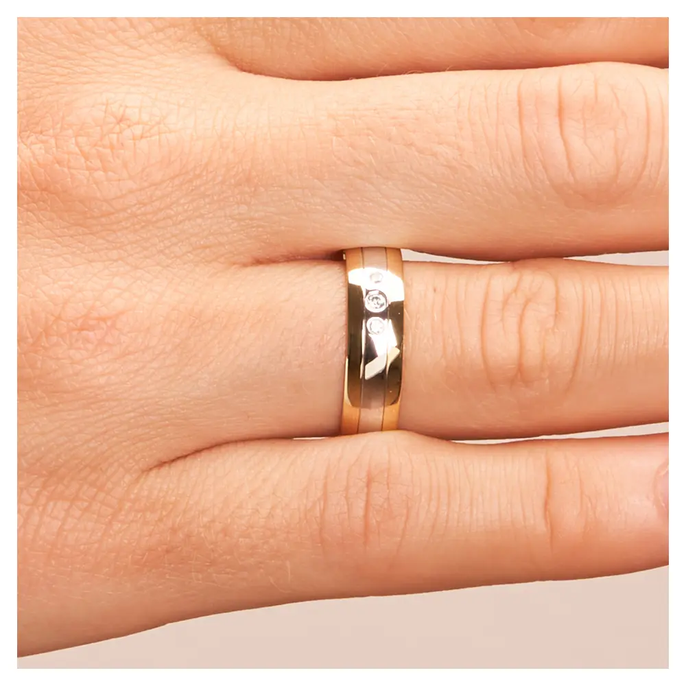 Trauring aus Weißgold und Gelbgold mit glänzenden Diamanten auf Hand im Zoom