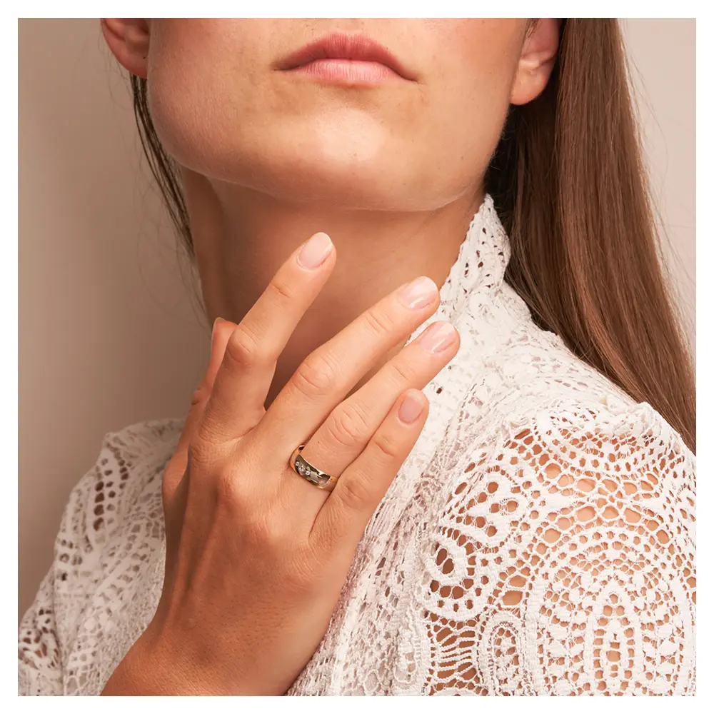 Trauring aus Weißgold und Gelbgold mit glänzenden Diamanten auf Hand am Gesicht