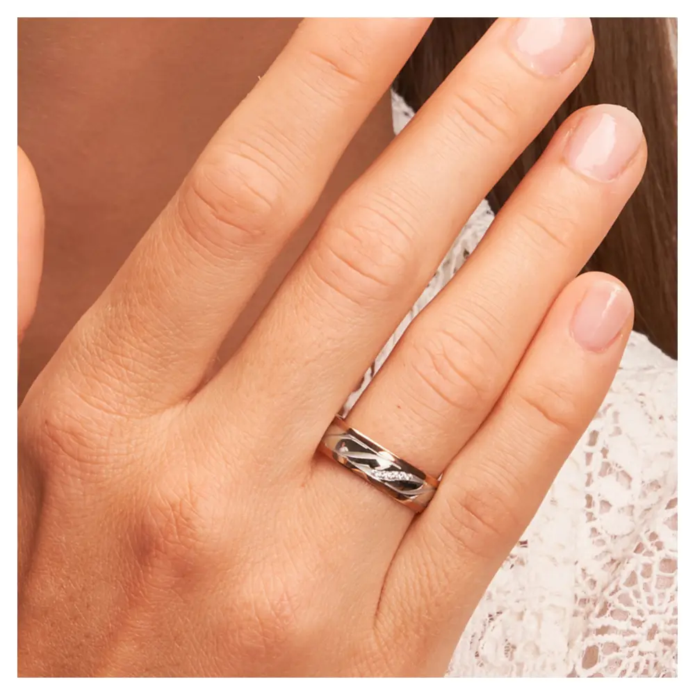 Ehering in Palladium 500 & Rotgold mit schrägen Rillen und Diamanten auf Hand am Gesicht im Zoom