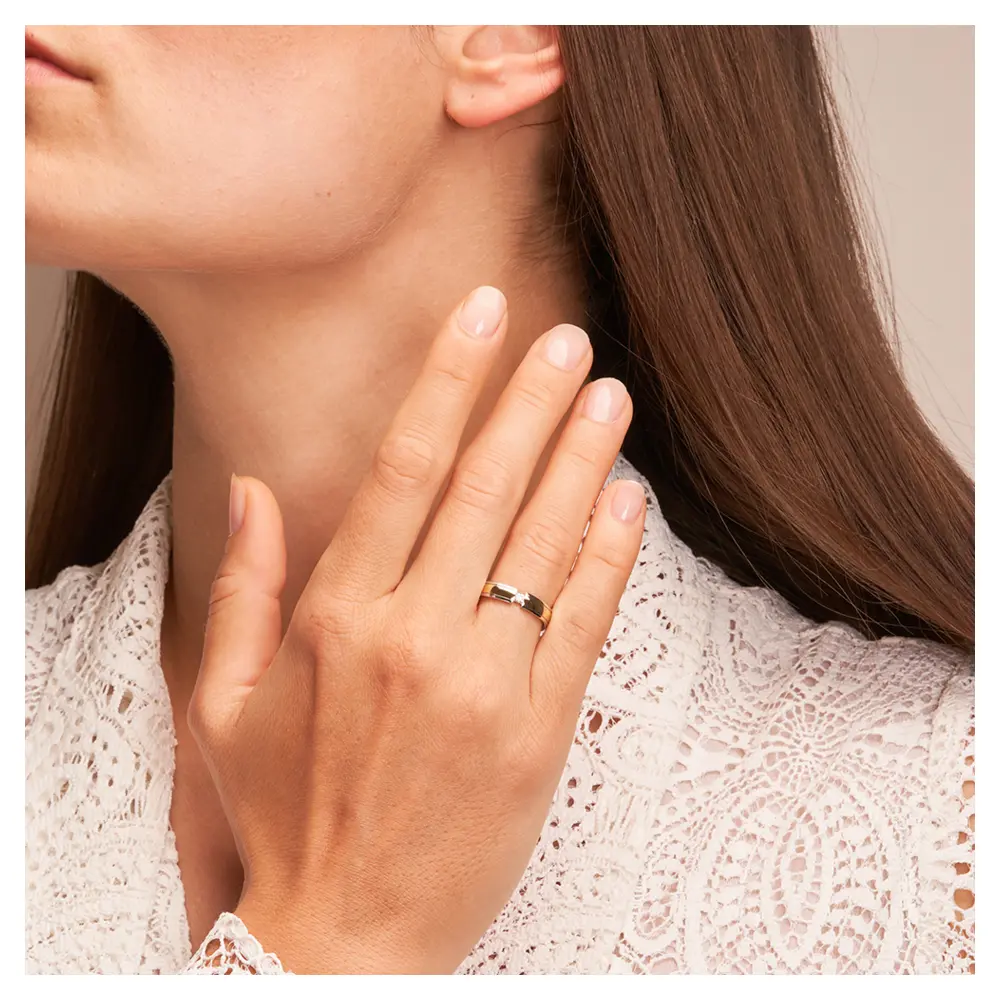 Ehering aus Weißgold und Gelbgold mit rundem Diamanten auf Hand am Gesicht
