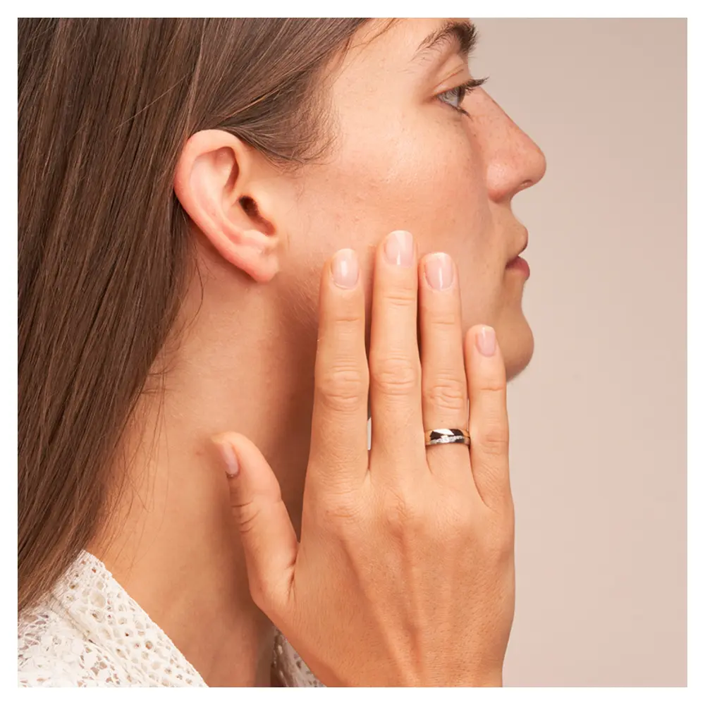 Ehering in Rotgold und Palladium 500 mit 7 strahlenden Diamanten auf Hand am Gesicht