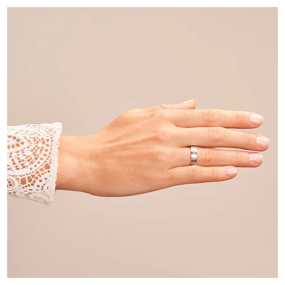 Längsmatte Eheringe aus Weißgold mit Rille und Diamanten auf Hand